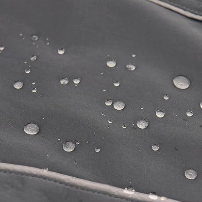 Water droplets beading on the black waterproof shell of the dog coat